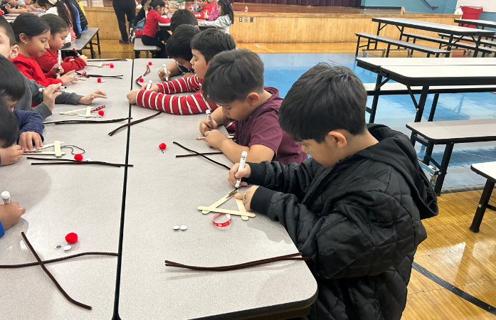 students sitting at cafeteria tables working on their reindeer ornaments
